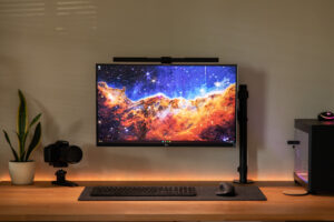 BenQ ScreenBar Plus LED monitor light bar mounted on a monitor, illuminating a home office desk